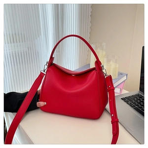 Detail of red lychee grain leather handbag with silver hardware and adjustable strap
