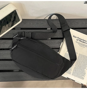 Detail of black nylon waist bag featuring adjustable strap and woven zipper puller