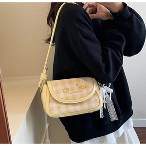 Detail of yellow plaid crossbody bag featuring pearl lace charm and heart embroidery