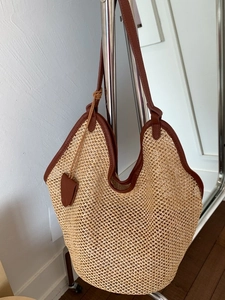 Large beige woven straw tote bag with brown leather straps for beach holidays