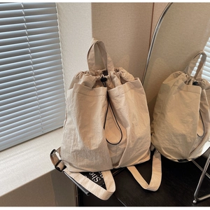 Detail of minimalist beige drawstring backpack with side pockets and smooth texture