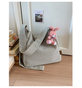 Detail of high-capacity woven canvas tote bag in oatmeal with plush bunny pendant charm