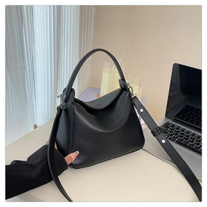 Close-up of black litchi pattern leather bag with adjustable strap and silver buckles