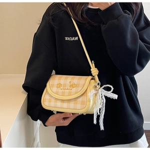 Detail of yellow plaid crossbody bag featuring bear embroidery and lace pearl pendant