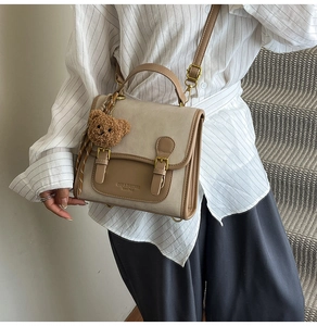 Close-up of retro color-block backpack with brown leather trim and cute bear charm