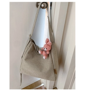 Detail of canvas tote bag side showing brown leather label and pink bunny plush keychain