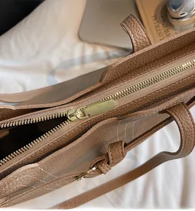 Close-up of the smooth gold metal zipper and lychee pattern leather on the tote bag