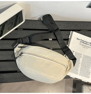 Detail of off-white nylon fanny pack with black adjustable strap and plastic buckle