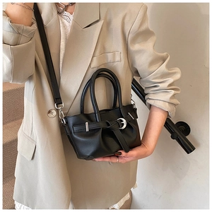 Détail d'un sac seau noir plissé avec boucles argentées porté par un mannequin chic