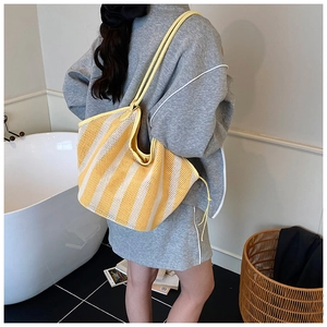 Detailed side view of yellow striped mesh tote bag styled with casual grey loungewear