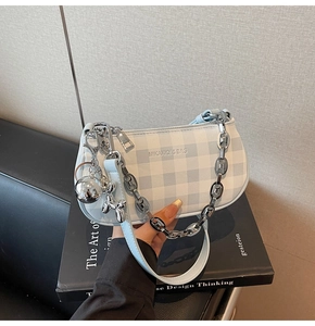 Detail of blue checkerboard bag with silver chain, balloon dog charm and metal ball
