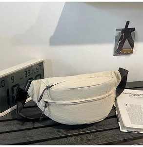 Close-up of cream nylon chest bag featuring natural wrinkled texture and black zippers