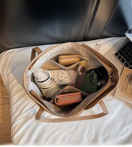 Macro view of beige tote bag interior showing large capacity and zipper compartments