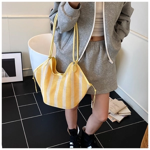 Detail of yellow and white striped mesh woven tote bag with adjustable side drawstrings