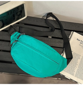 Close-up of bright green nylon crossbody chest bag with adjustable strap on wooden table
