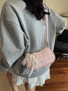 Sac sous le bras à carreaux roses avec nœud en dentelle et perles porté par le modèle