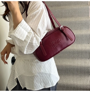 Detail showing the burgundy leather texture and embossed lettering on the shoulder bag