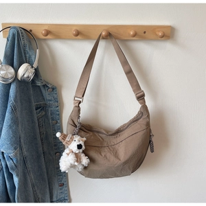 Detail of coffee brown nylon dumpling bag with adjustable strap and plush puppy charm