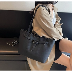 Detailed view of black lychee leather tote bag with stylish belt and metal ring buckle