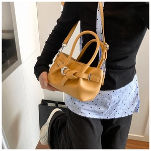 Détail du sac seau jaune gingembre avec boucle en cuir et finition à texture lisse