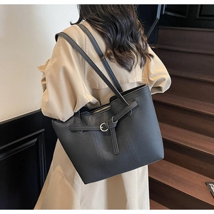 Detailed view of the black pebbled leather tote bag with metallic buckle and shoulder straps