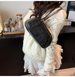 Detail showing the adjustable leather strap and embossed logo on the black shoulder bag