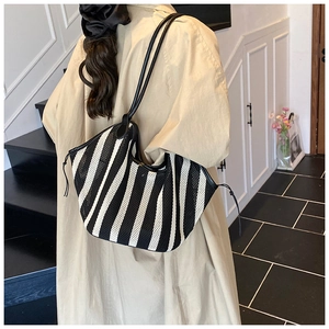 Detail view of woven mesh tote bag with black stripes and leather shoulder straps