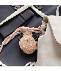 Détail d'un porte-clés ours en peluche avec corde tissée sur un sac à dos à carreaux