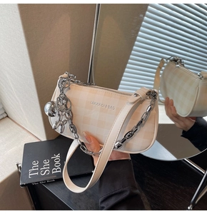 Detail of beige checkered handbag with silver chain and balloon dog charm on a side view