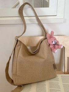 Minimalist khaki canvas tote bag with pink bunny charm and wide shoulder strap