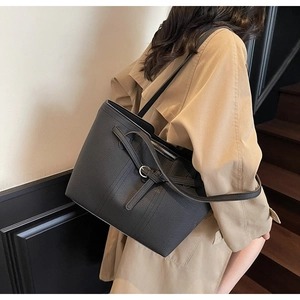 Close-up of black lychee grain leather tote bag with silver buckle and metal zipper
