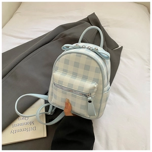 Détail d'un mini sac à dos à carreaux avec un nœud décoratif et une poche zippée avant