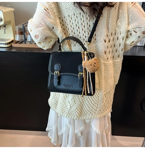 Detail of black matte leather mini square bag with vintage buckles and bear charm