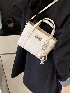 Borsa a secchiello minimalista in pelle bianco crema con ciondolo a perla e bambola