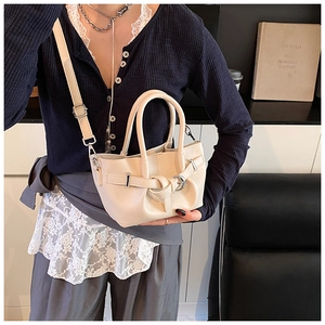 Détail du sac seau plissé crème montrant la bandoulière et la boucle métallique