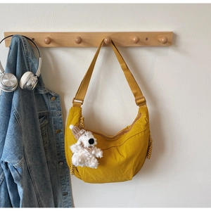 Detail of yellow nylon crescent bag with adjustable strap and cute plush bear charm