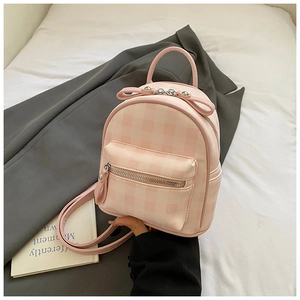 Détail d'un mini sac à dos à carreaux avec nœud décoratif et poche avant zippée
