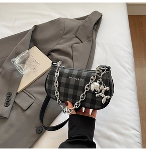 Detail of checkered shoulder bag with silver chain and artistic balloon dog charm