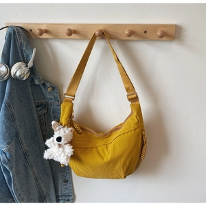 Detailed view of yellow crescent nylon bag with adjustable strap and cute plush bear charm