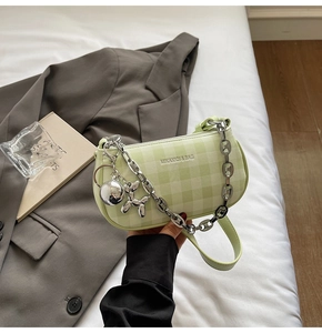 Detailed view of green plaid leather handbag with silver chain and metal dog charm