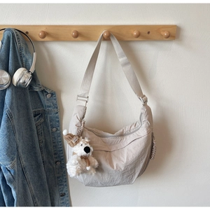 Detail of beige crescent crossbody bag with adjustable strap and cute plush bear charm