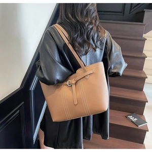 Detail of caramel brown leather tote bag showing lychee grain texture and metal ring buckle