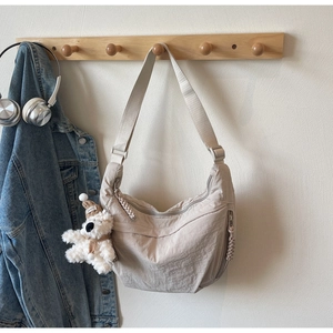 Detail of beige nylon crescent crossbody bag with adjustable strap and cute bear charm