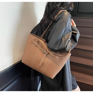 Detail of brown lychee grain leather tote bag with white contrast stitching and buckle straps