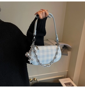 Detail of blue and white gingham bag featuring a silver chain and balloon dog charm