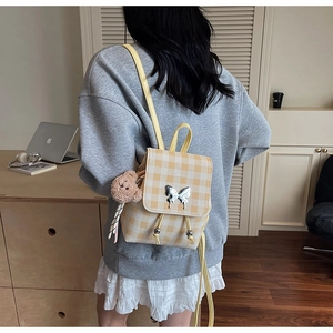 Détail du mini sac à dos à carreaux jaunes avec boucle papillon et breloque ours peluche