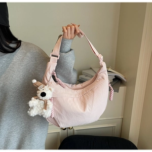 Pink nylon crescent crossbody bag with wide strap and cute teddy bear pendant detail