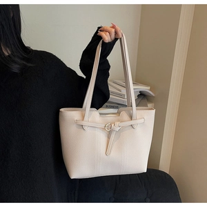 Detail of light beige lychee pattern tote bag with golden buckle and sleek stitching