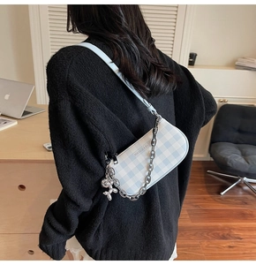Detail of light blue checkered crossbody bag with silver chain and balloon dog charm