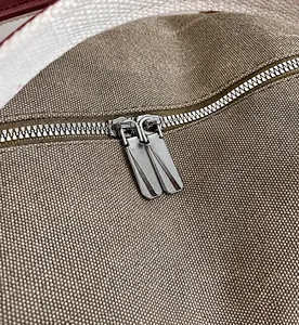 Close-up of smooth metal double zippers on a durable canvas travel duffel bag